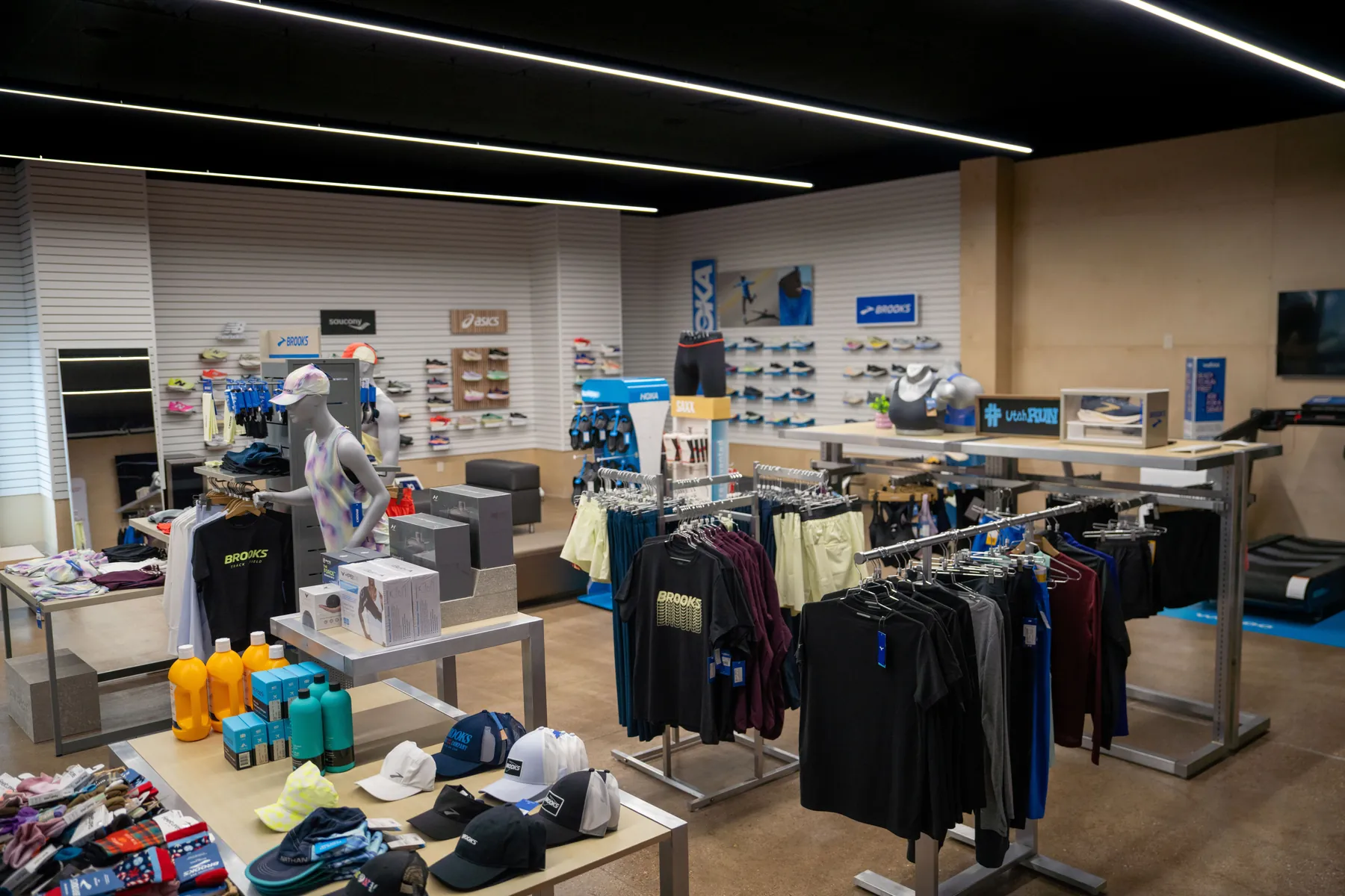 Inside UtahRUN, apparel tables and racks in front of the shoe walls