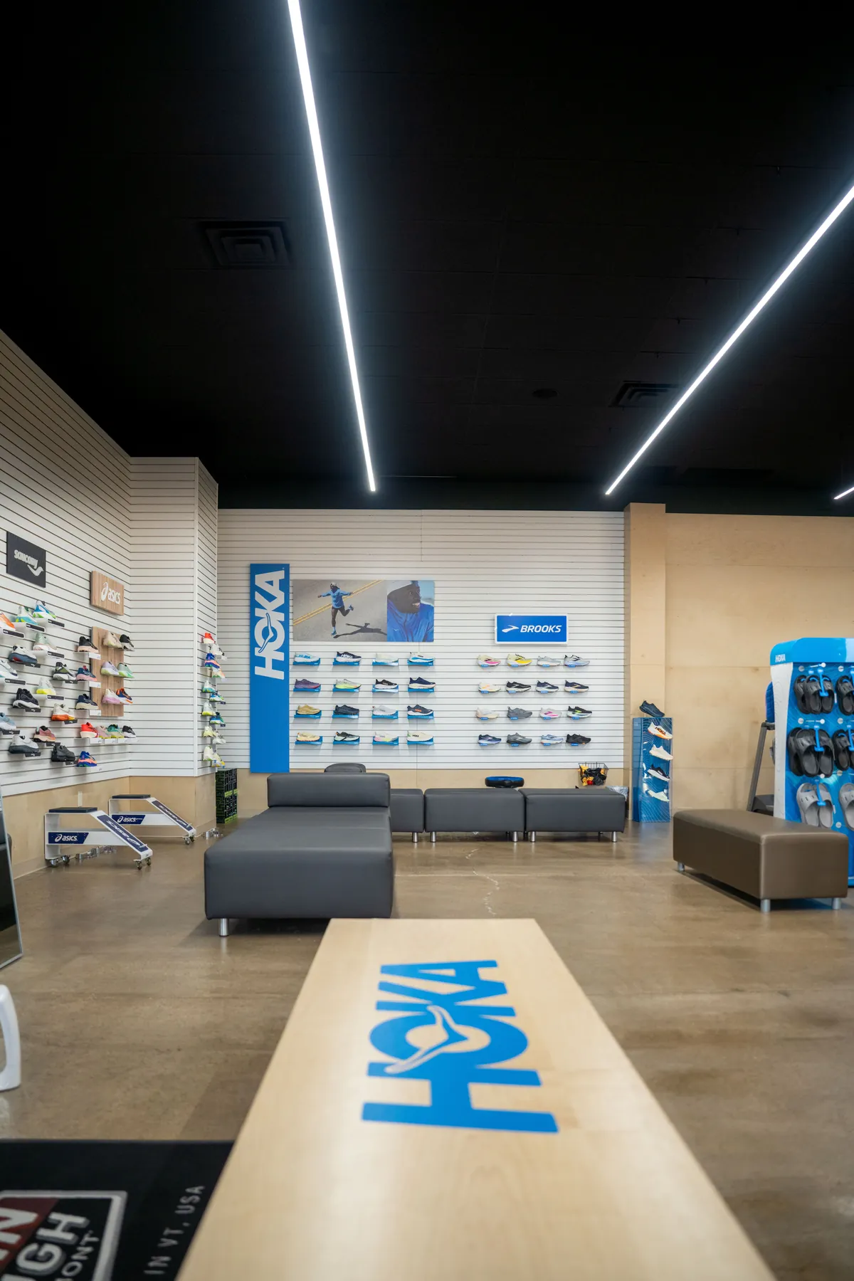 The fitting area at UtahRUN, a HOKA-branded bench and seating in front of the shoe wall