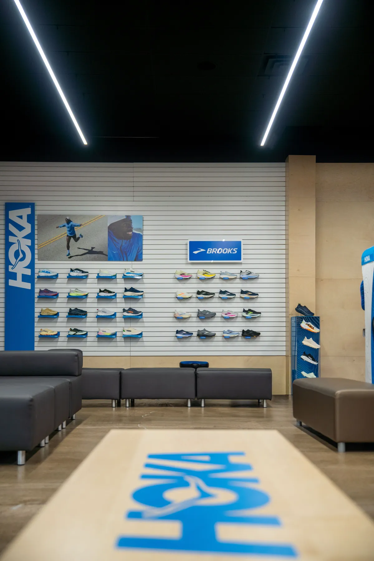 Try-on seating at UtahRUN facing the HOKA wall, a HOKA rug on the floor